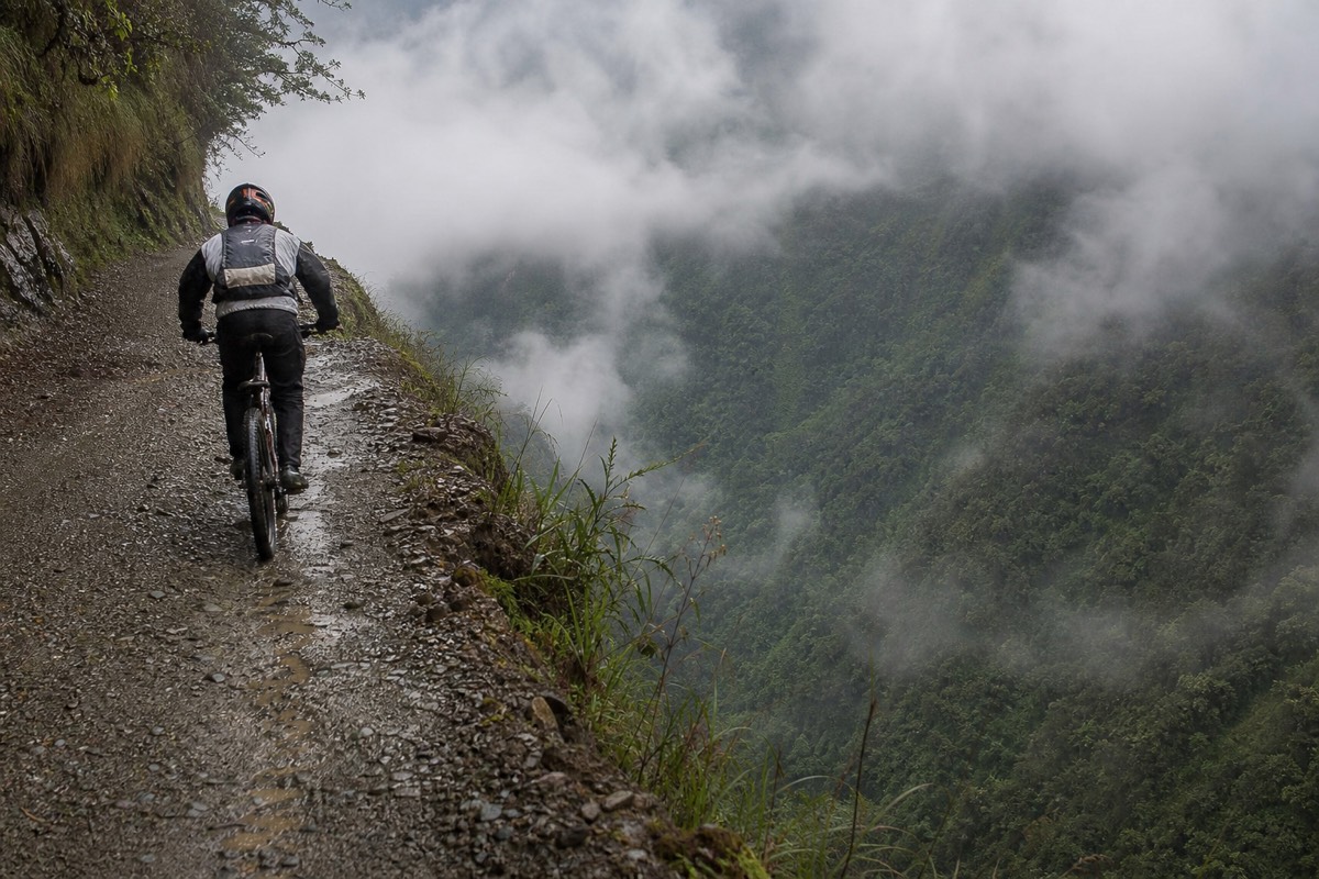 A mountain biker riding the cliff edge of the Death Road high above the valley